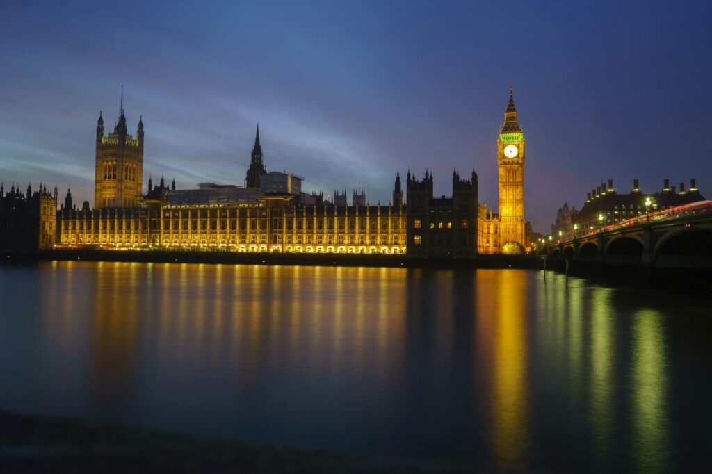 Night view of Big Ben and the Houses of Parliament illuminated, reflected in the Thames River, London.