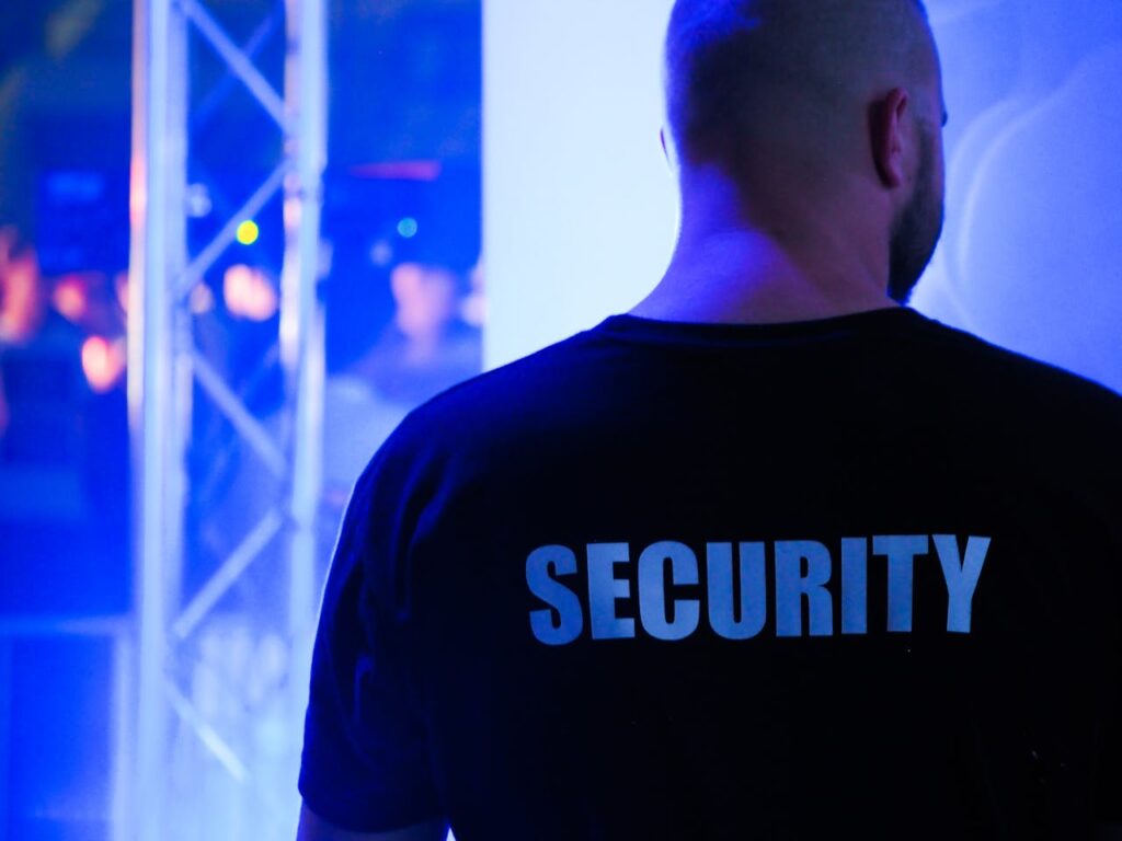 A security guard wearing a black shirt in a dimly lit nightclub.